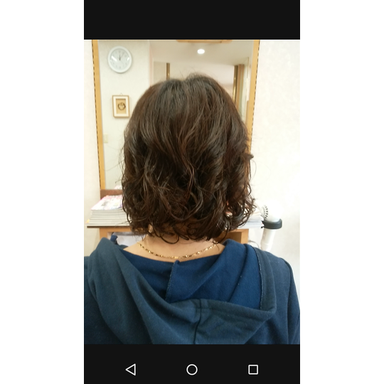 肩につくぐらいのレイヤーカットにパーマをかけている