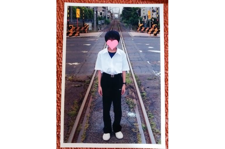 踏切の歩道の線路の上に立っている少年を正面から接写