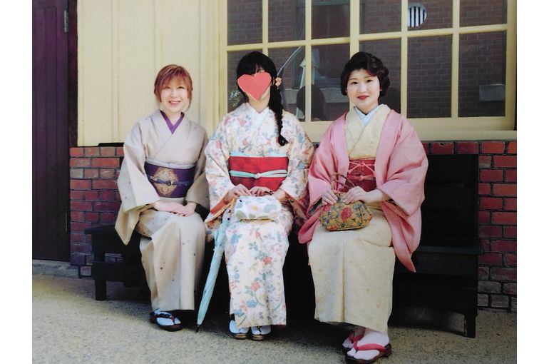 ベンチに座る３人 後ろに黄色い壁の建物