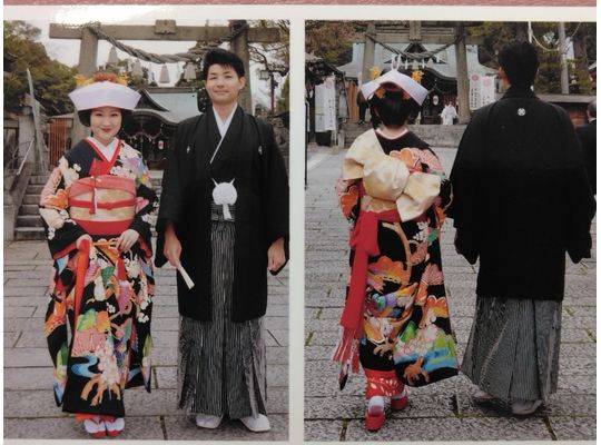 黒本振袖の花嫁がお引きずりの裾をからげて右手で持っている。隣に新郎。正面と後ろ姿の2枚