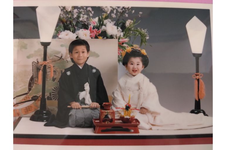 ３歳 白打掛姿の妹(角かくし綿帽子無し)、6歳 黒紋付羽織袴姿の兄、二人かしこまって笑顔