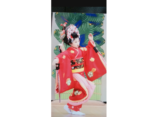 赤い着物、豪華な髪飾りの女の子がステージで踊っている