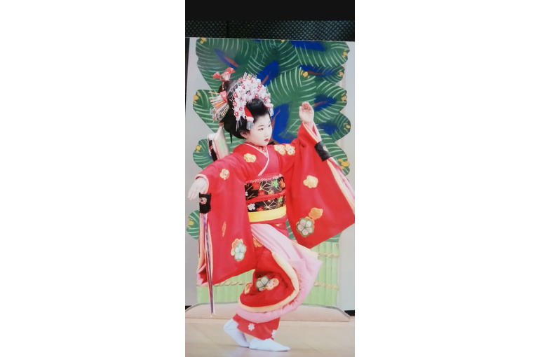 赤い着物、豪華な髪飾りの女の子がステージで踊っている