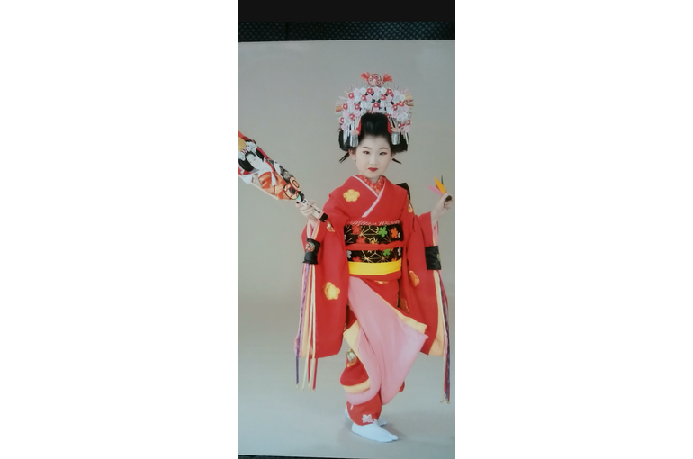 赤い着物の女の子が右手に羽子板左手に羽根を持ってポーズをとっている
