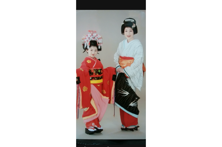 白い着物のお引きずりの裾をからげて手に持って隣に立っている母親