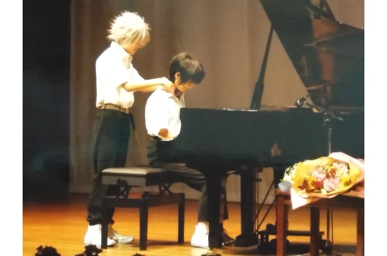 カヲル役が椅子の後ろからシンジ役の首のチョーカーに両手をかける